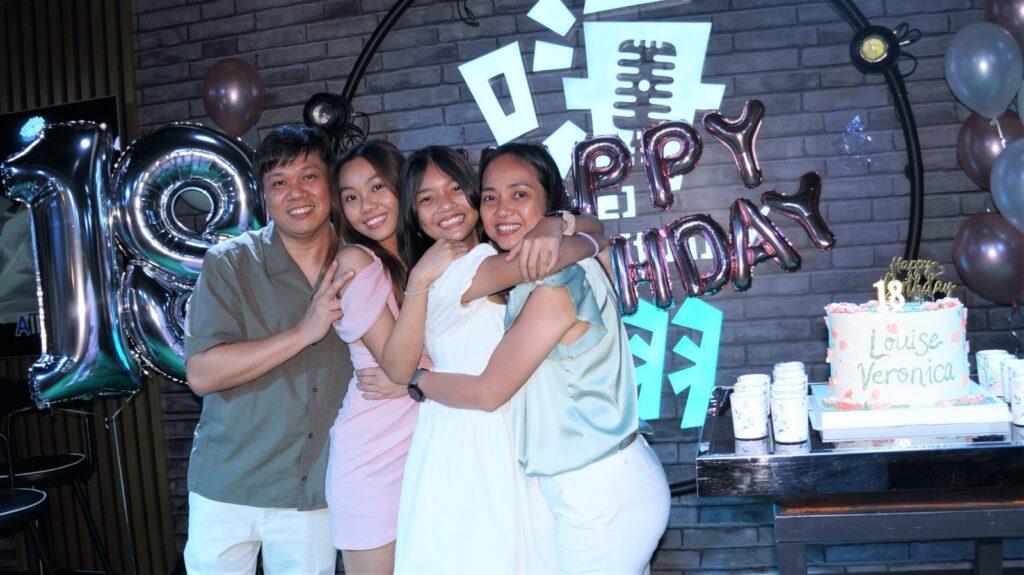 A happy family of four smiles and laughs while gathered around a colorful birthday cake at the HaveFun Toa Payoh outlet. Balloons and decorations add to the festive atmosphere as they enjoy celebrating together.